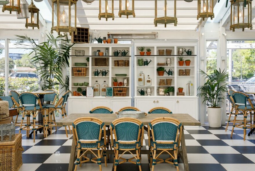 Interior of the Conservatory with black and white check tiled floor, white furnishings, and large windows with views to garden.