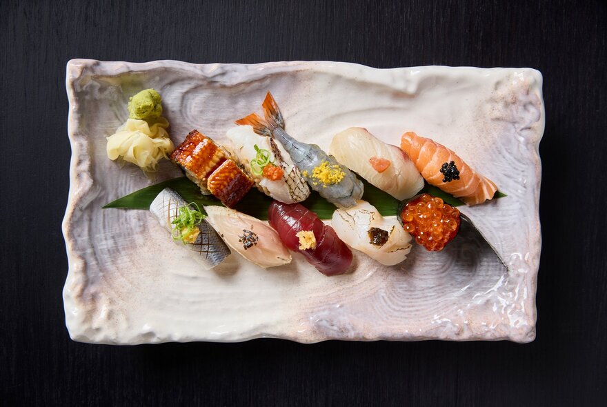 A mix of sushi on a white, textured plate. 
