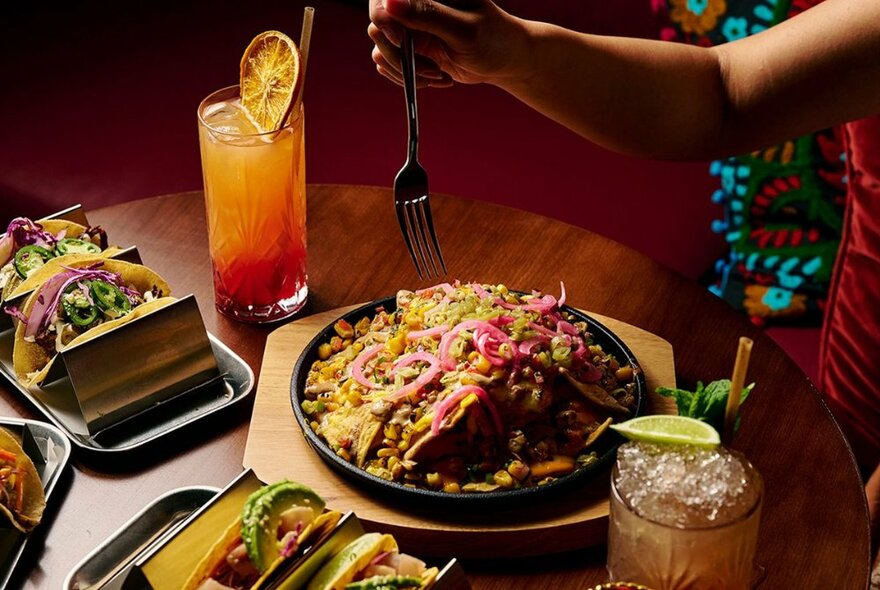 A table with plates of Mexican foodand cocktails. 