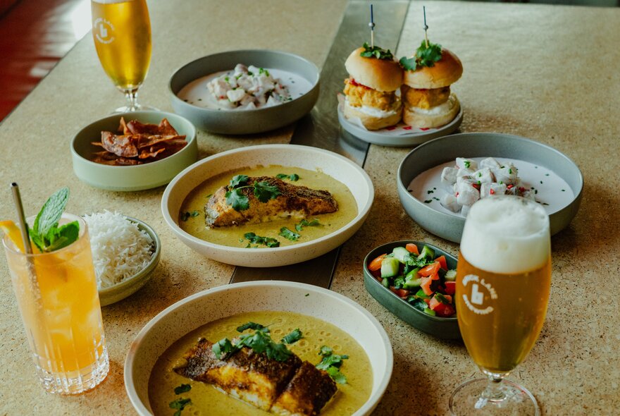 An array of dishes and drinks including fish with soup and burgers.