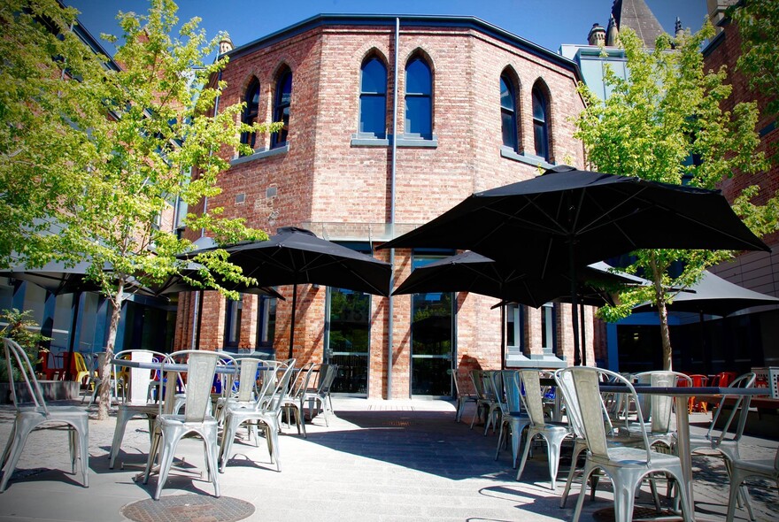 Exterior of Pearson and Murphy's Cafe with silver chairs and large black umbrellas.