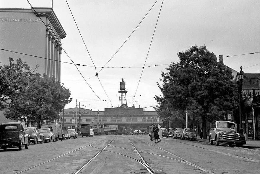 Black and white vintage image of a very wide Melbourne city street, with cars on either side, and a building in the background.