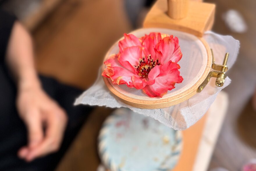 Floral accessorie made from silk and beads, clamped in embroidery tool,