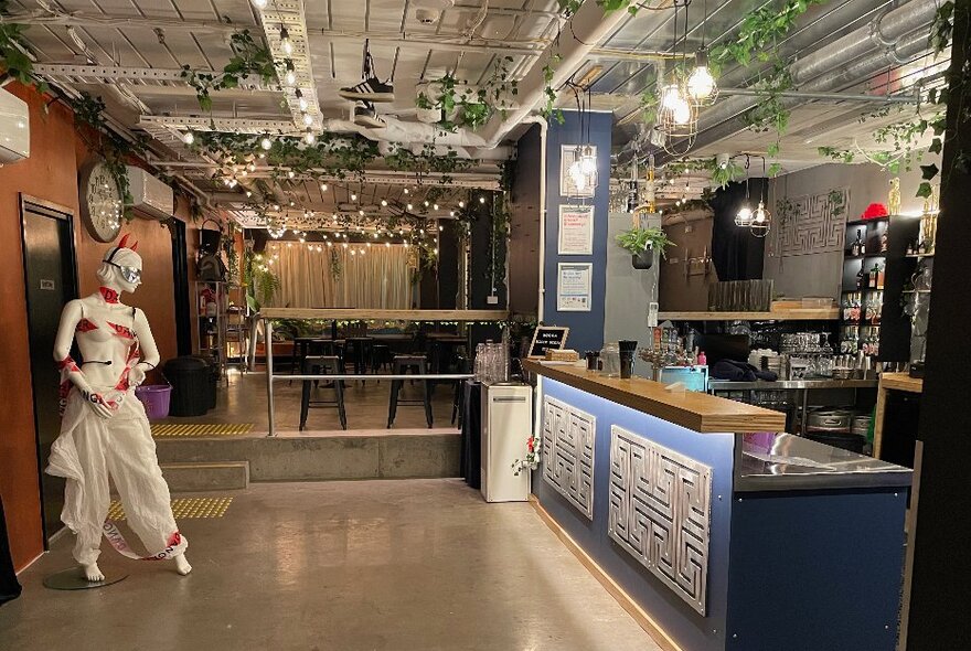 Industrial-style bar area with seating, tables and life-size mannequin.