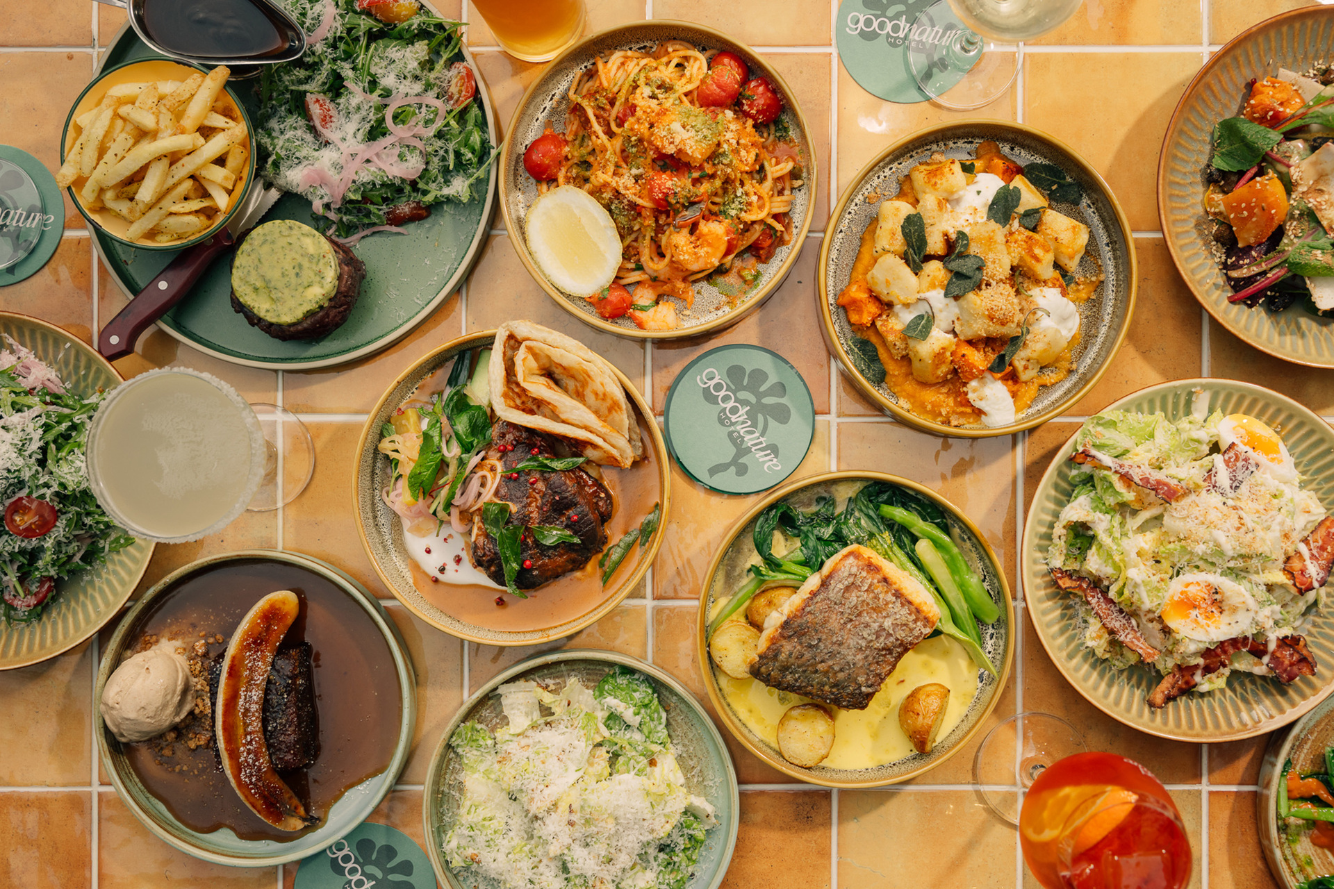 A table featuring plates of food in a restaurant including past, fish, fries and salad