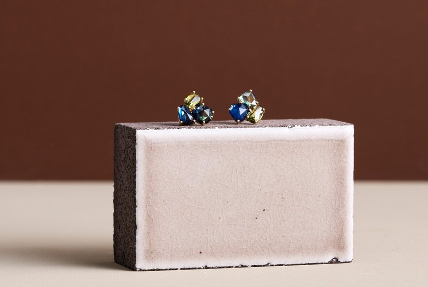 Two sapphire earrings resting on a grey rectangular display.