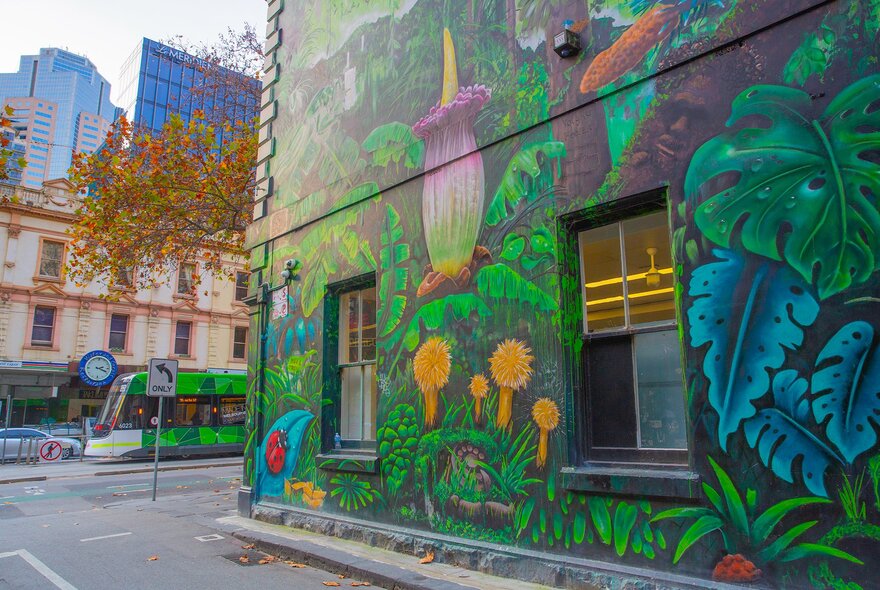 A green nature mural on a laneway wall.