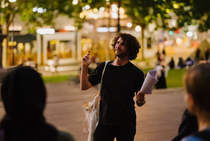 A person leading a guided evening walk at around University of Melbourne campus spaces.