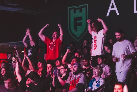 An audience at Fortress Arena watching a sports game on the big screen and cheering.