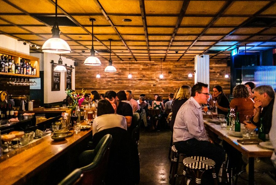 A busy bar with timber details warm lighting.