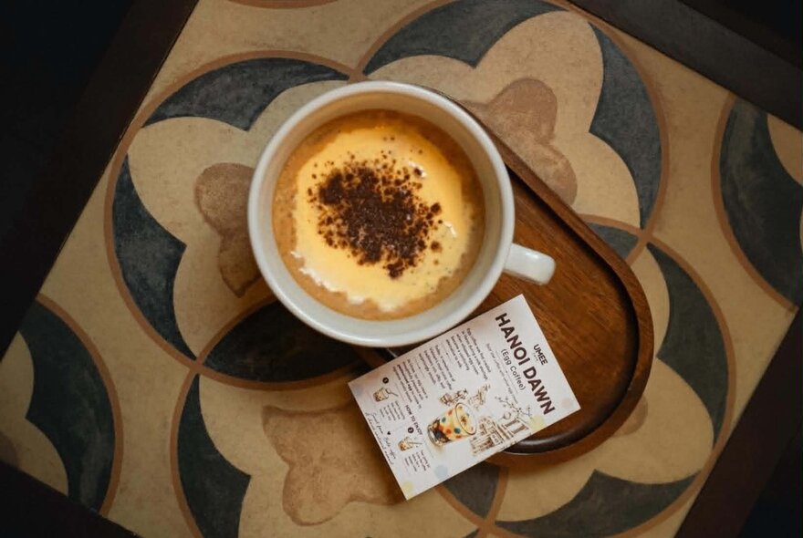 Looking down from above at a traditional Vietnamese egg coffee served with a cocoa-dusted creamy top.