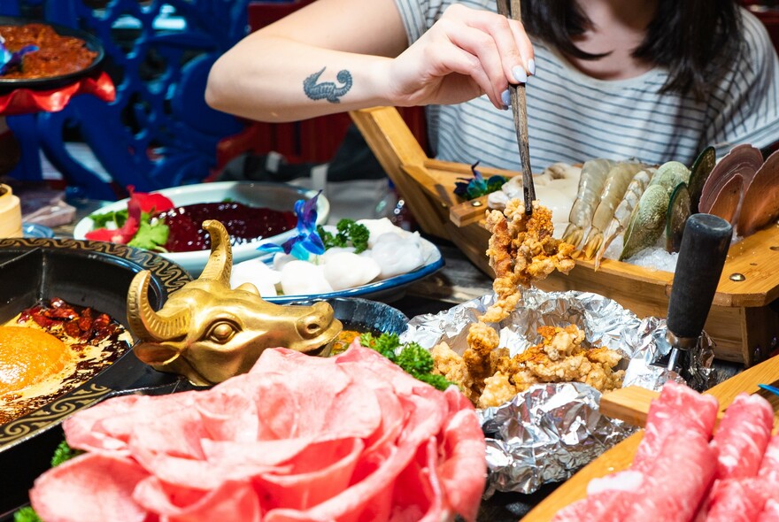 Person using chopsticks to select ingredients for a Sichuan hotpot dish.