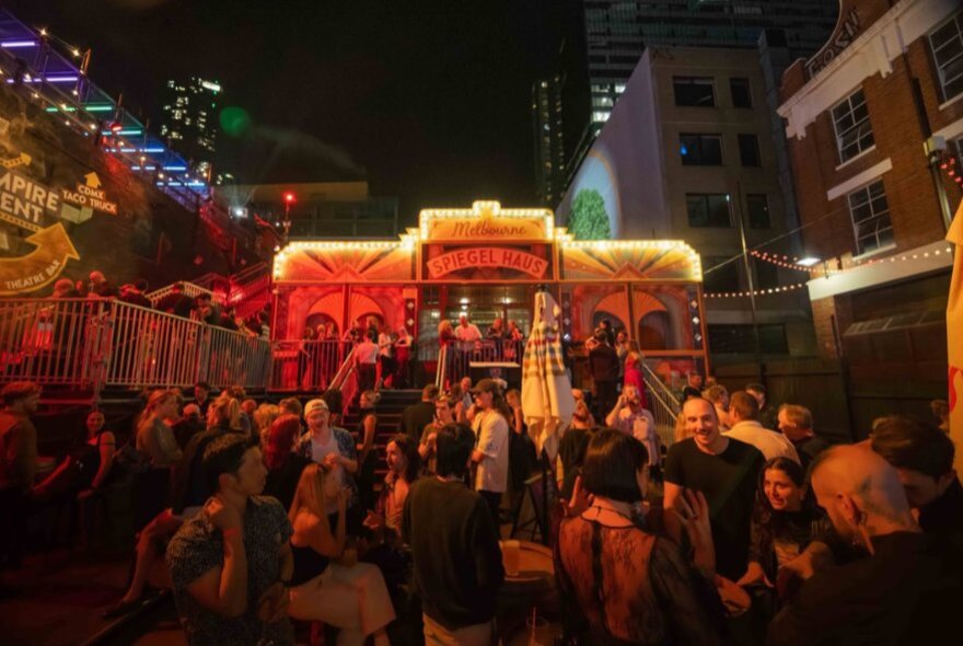People gathered at the Spiegeltent under the Melbourne skyline. 