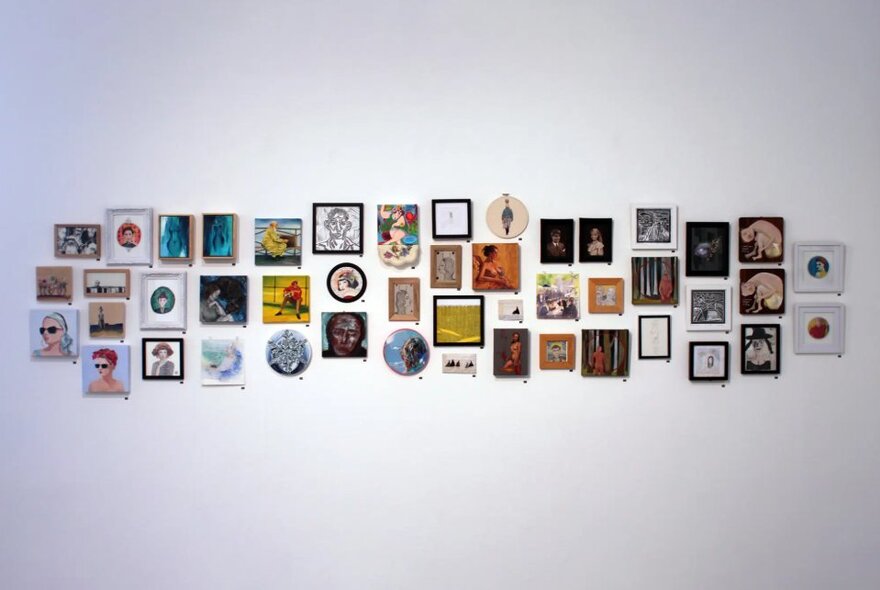 A gallery wall with many small artworks hung closely together.