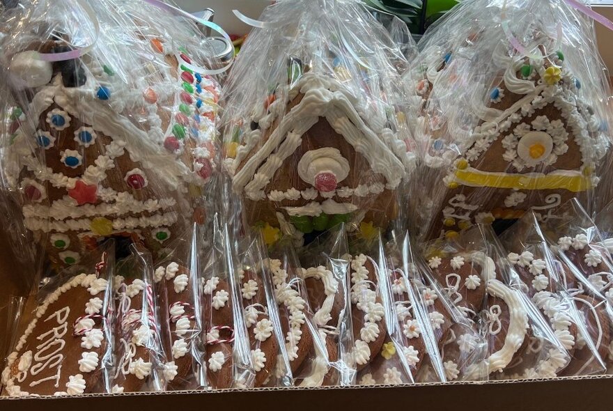 Decorated gingerbread houses and cookies packaged up for sale at a stall.