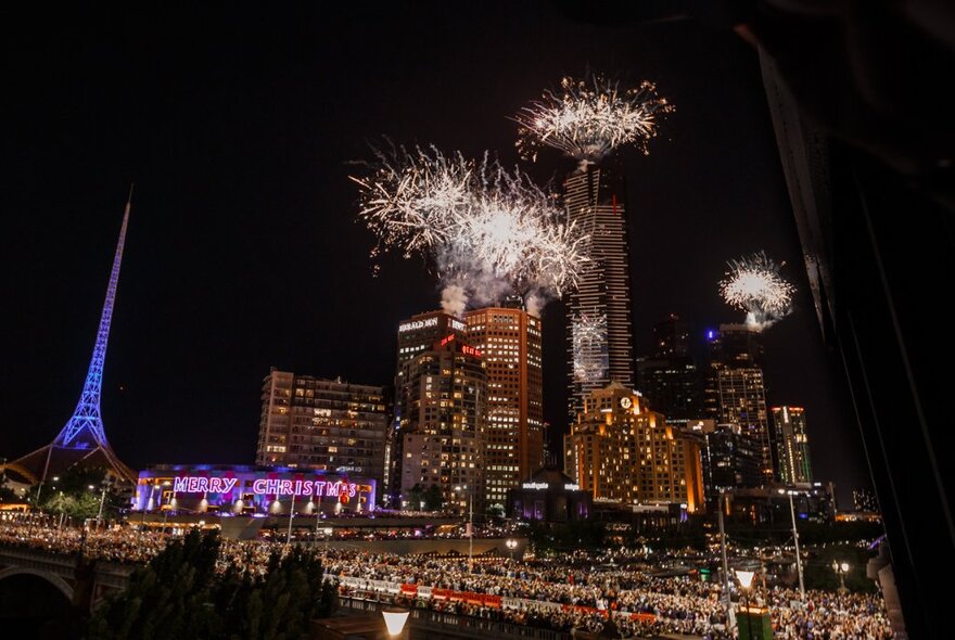 Fireworks from a rooftop with Arts Centre spire and buildings at night.