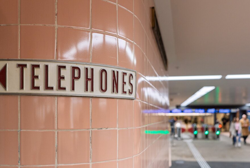 The classic pink tiles of Campbell Arcade with an old sign saying TELEPHONES with an arrow. 