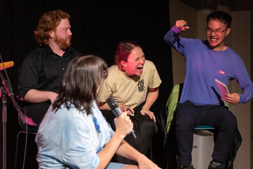 Four comedians sitting in a group, all laughing hysterically.