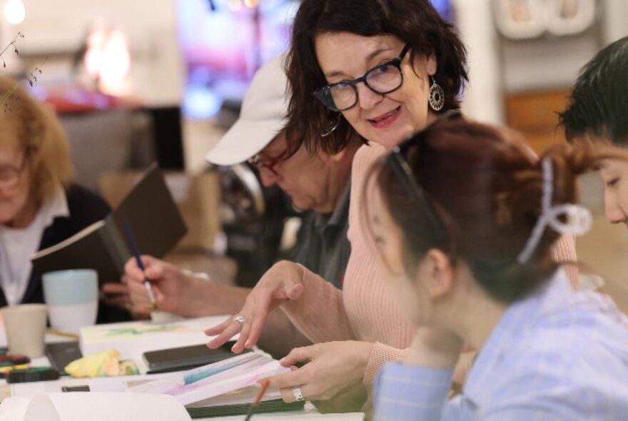 .People at a table interacting and painting.