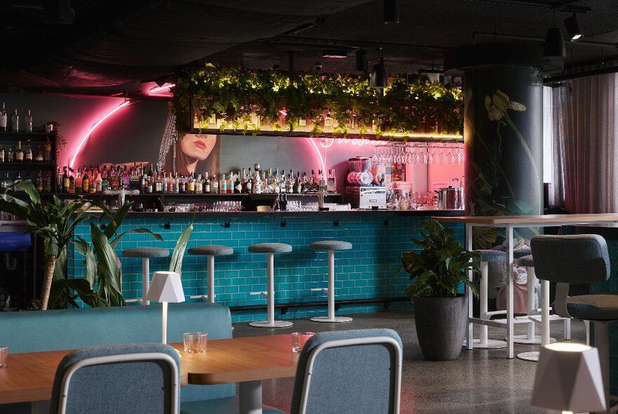 A blue tiled bar with a warm pink neon decorating the bar area.