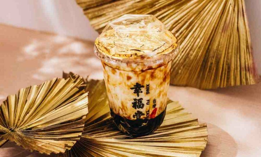 A container of bubble tea with gold leaf on top