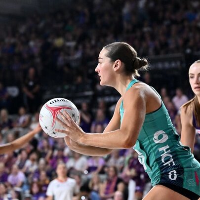Women's netballers during a game, one player holding the ball while others surround her.