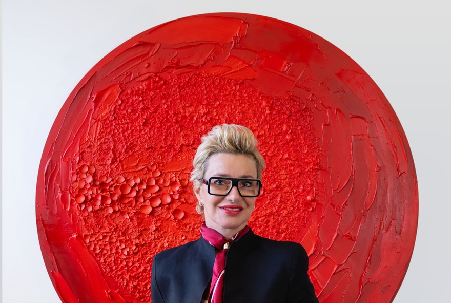 A person standing in front of a large, textured red circular artwork.