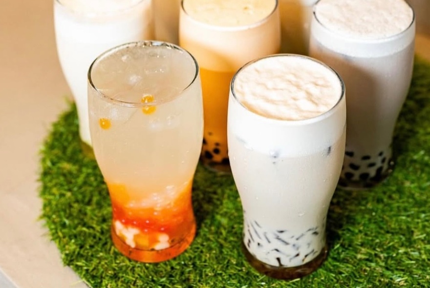 Different flavours of bubble tea served in pint glasses, sitting on green Astroturf.