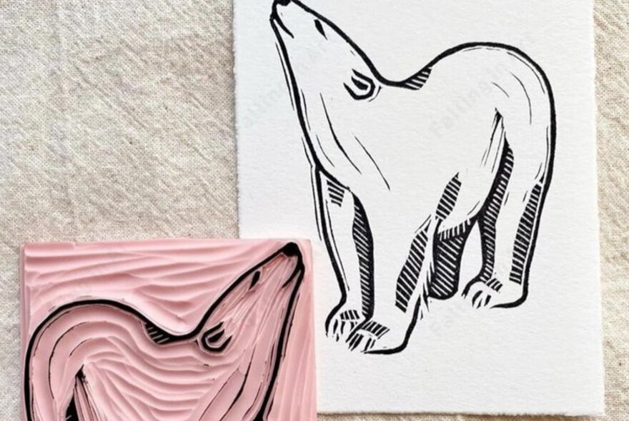 A linocut of a polar bear and printed results on paper.