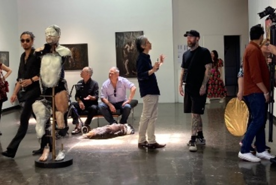 Interior of a exhibition space at an art fair, with people looking at artworks, walking around and interacting with each other.