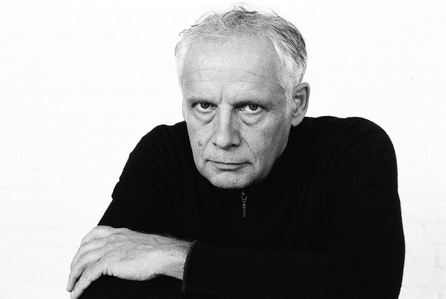 Dutch  cellist Pieter Wispelwey looking stern with arms folded, wearing a black jumper.