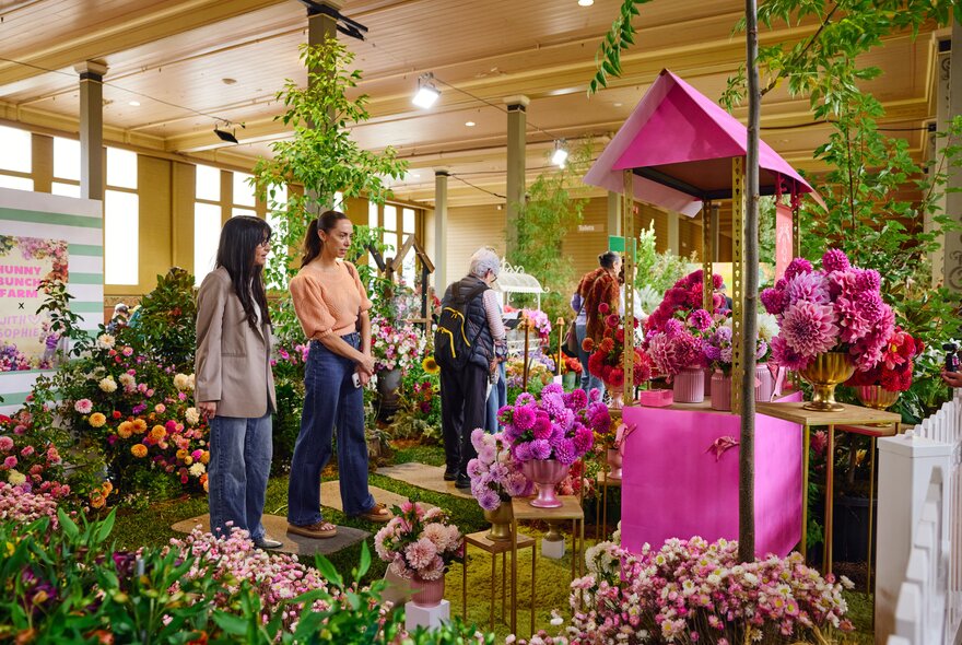 Two women looking at floral arrangements in a flower exhibition.