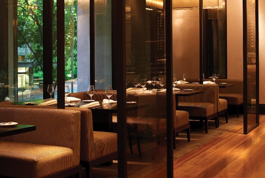 Booth seating in a restaurant with dark wood details and view to trees outside.