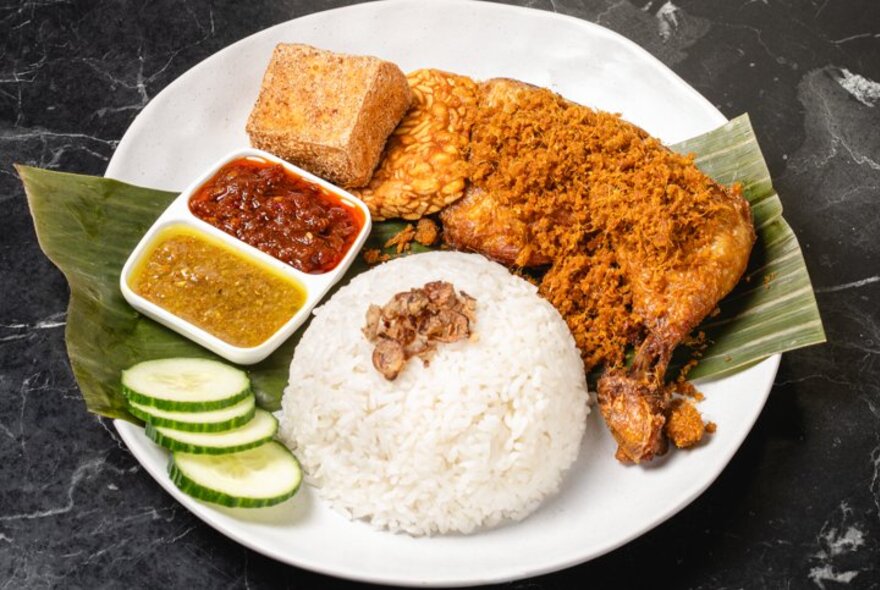 Fried puffs on a plate with condiments and rice.
