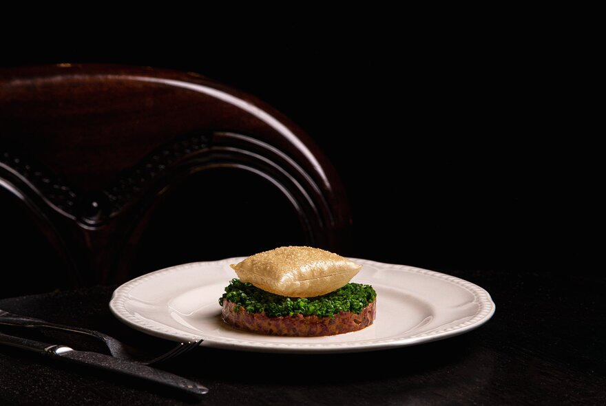 A plate of food in a fine dining restaurant with dark walls. 