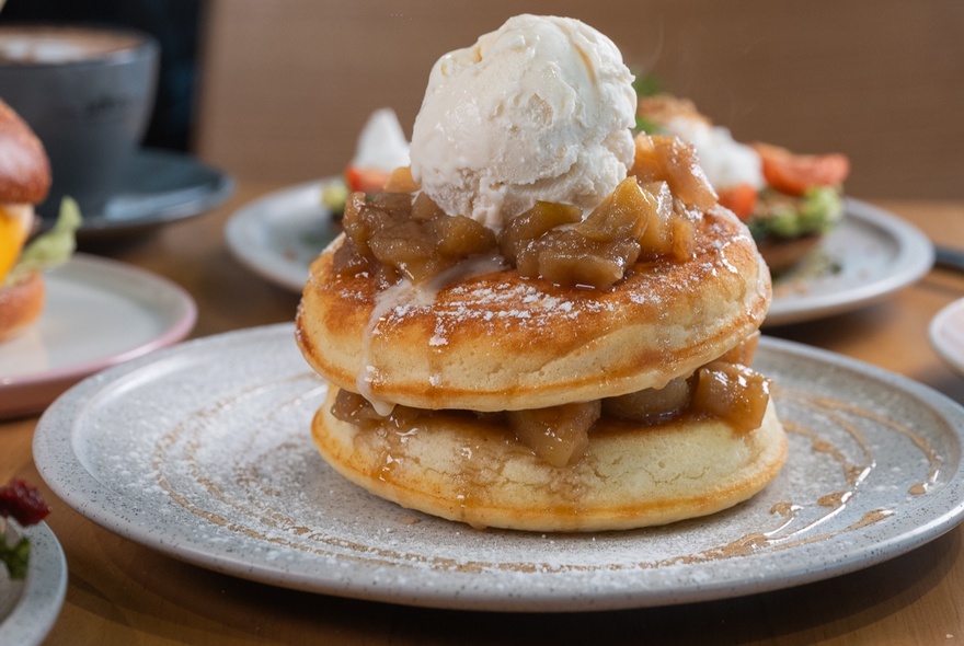 Two stacked pancakes with stewed fruit and a scoop of ice-cream on a plate.