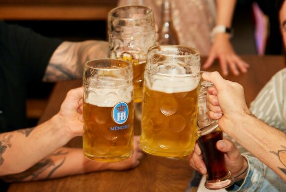 three large steins of beer being clinked