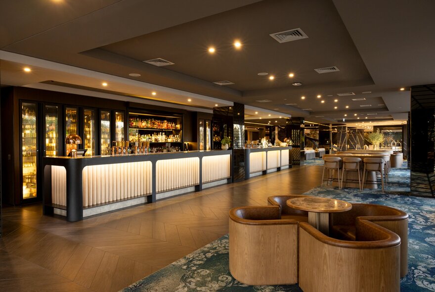 Bar area of the Pullman East Melbourne, showcasing modern, illuminated bar frontage and comfortable lounge seating.