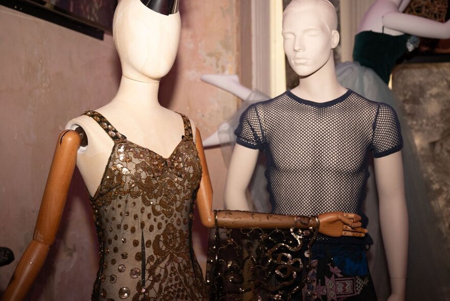 A male mannequin in a mesh t-shirt alongside a female mannequin wearing a sheer dress.