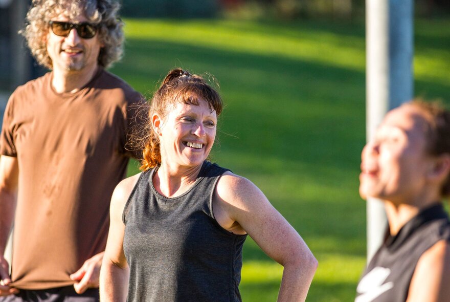 Three people engaging in fitness activities at a football oval.