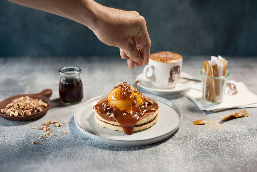 Pancake stack with syrup, scoop if ice cream and sprinkled nuts.