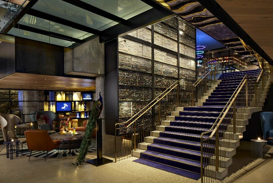 Hotel foyer with staircase leading to mezzanine level, with industrial-chic grey metal decoar.