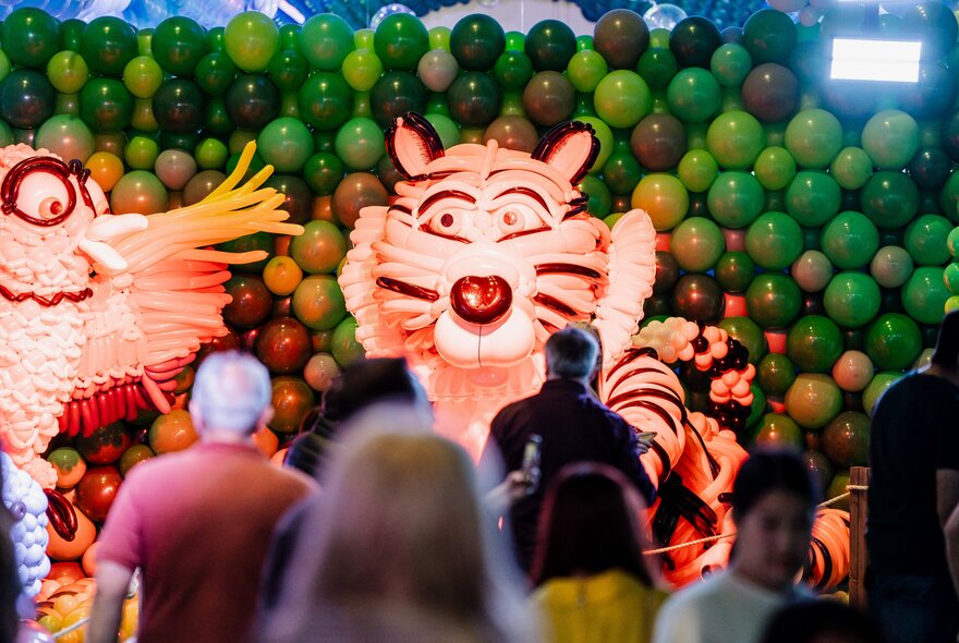 People in front of a display of animals, including a tiger, made from balloons.