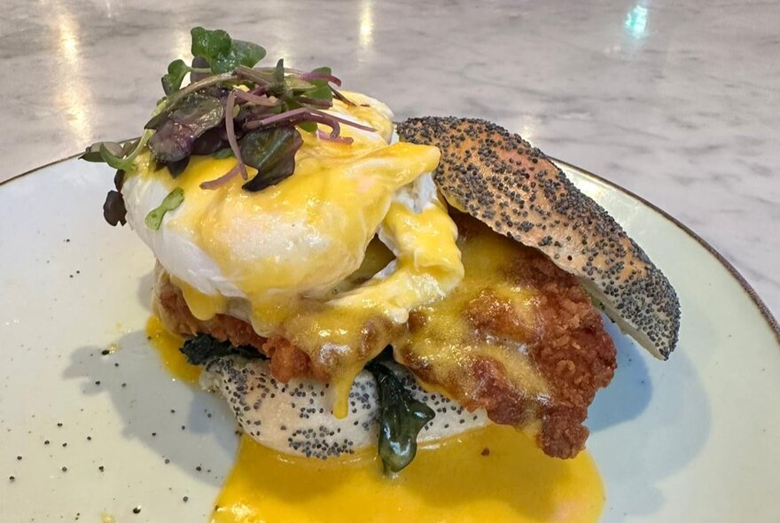 Pached eggs with hollandaise sauce on poppyseed roll.