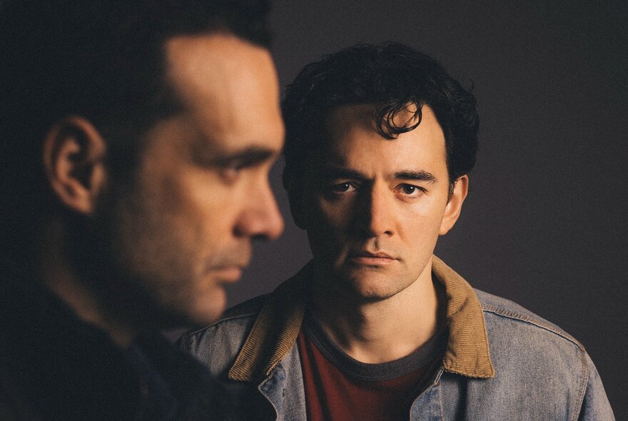 Two Maori men, one facing the camera, the other side on, looking across his line of vision.