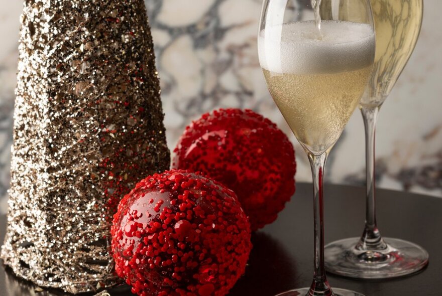 Two glasses of sparkling wine, placed along festive silver and red table decorations.