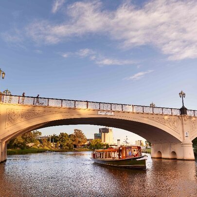 Boat travelling beneath a bridge on a river.