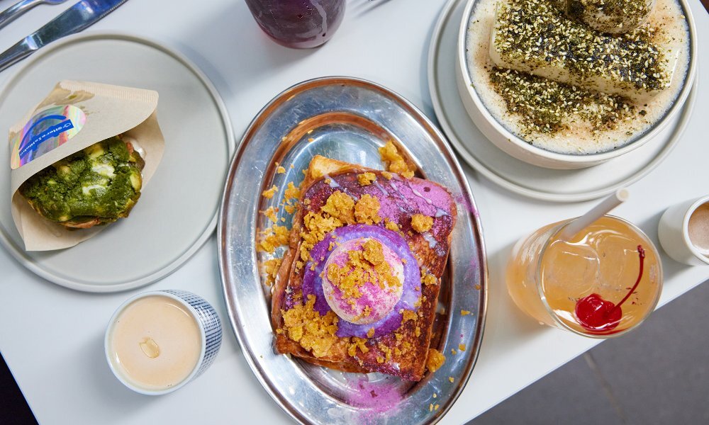 A table set with desserts and drinks including an ube topped toast.