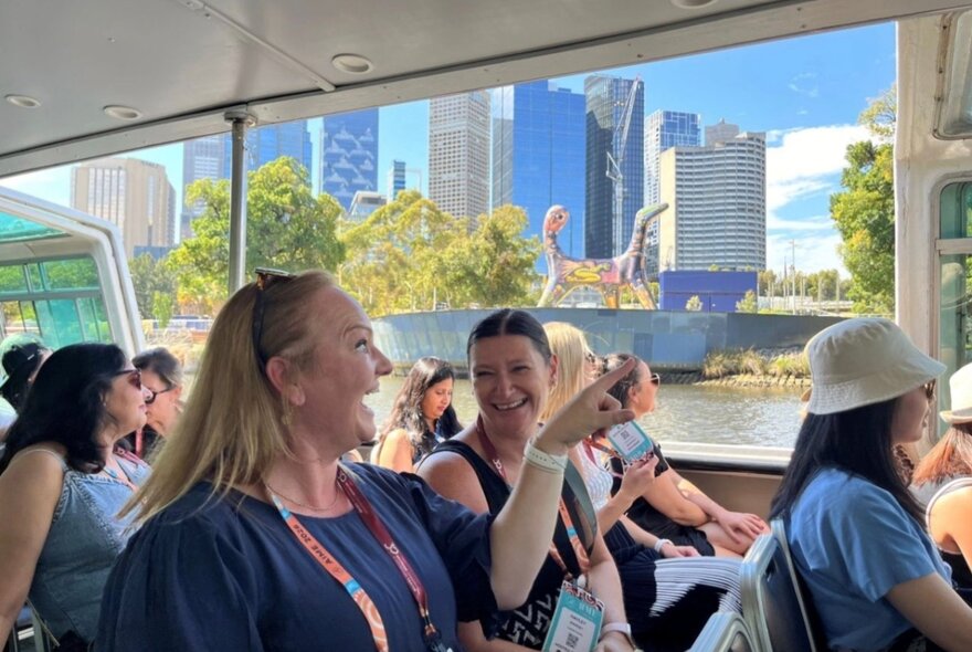 A group of smiling people enjoying a sightseeing cruise of Melbourne from a boat.