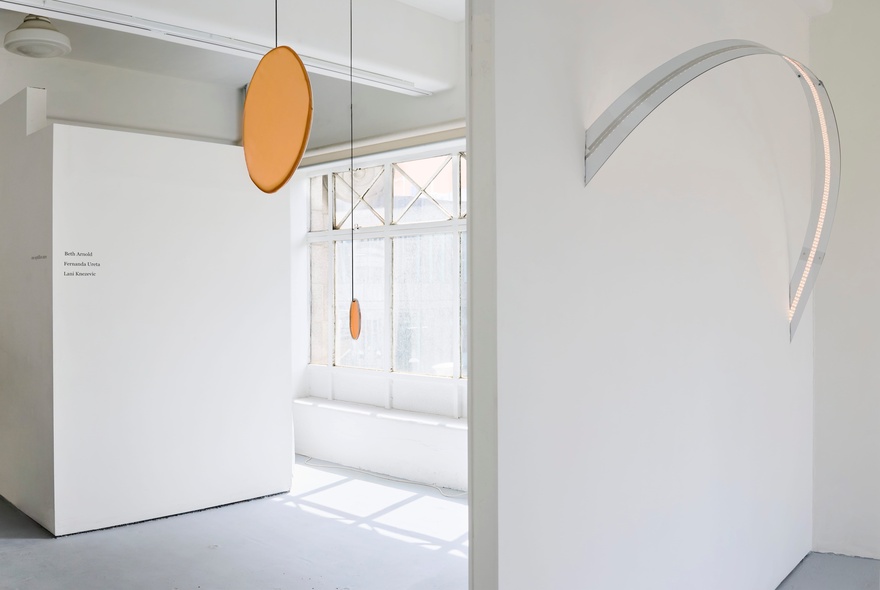 The white walls and light-filled gallery rooms at CAVES, with a large disc shaped sculpture hanging from the ceiling.
